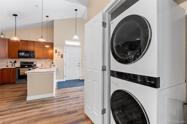8779 S Kipling Way Unit 204, Littleton, CO 80127 - washroom with stacked washer / drying machine, light wood-style flooring, a high ceiling, and baseboards