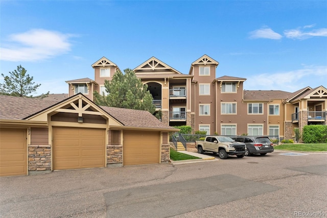 8779 S Kipling Way Unit 204, Littleton, CO 80127 - view of front of house featuring stone siding, a shingled roof, and community garages