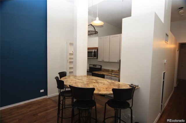 720 16th St Unit 513, Denver, CO 80202 - kitchen with stainless steel microwave, range with electric stovetop, a breakfast bar area, dark wood-style floors, and white cabinetry