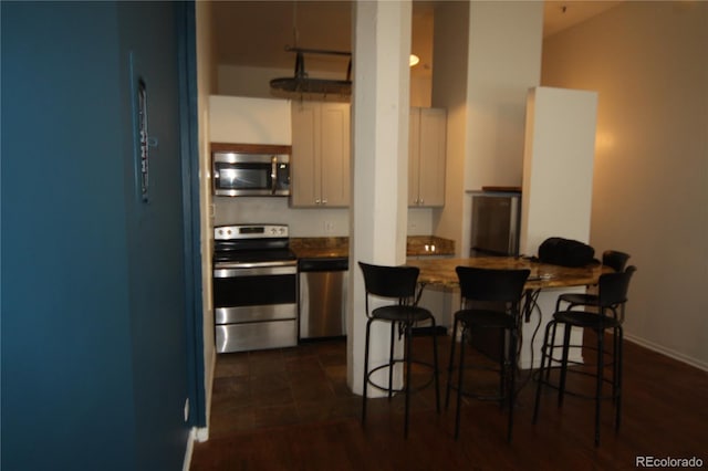 720 16th St Unit 513, Denver, CO 80202 - kitchen featuring appliances with stainless steel finishes, a kitchen bar, a peninsula, white cabinets, and dark wood-style floors