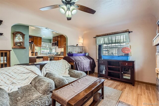 5704 Ammons St, Arvada, CO 80002 - living area with arched walkways, ceiling fan, light wood-style floors, and baseboards