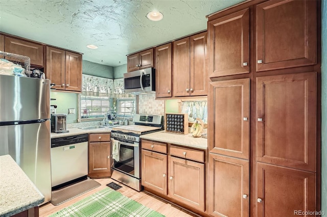 5704 Ammons St, Arvada, CO 80002 - kitchen with appliances with stainless steel finishes, light wood-style flooring, a sink, backsplash, and recessed lighting