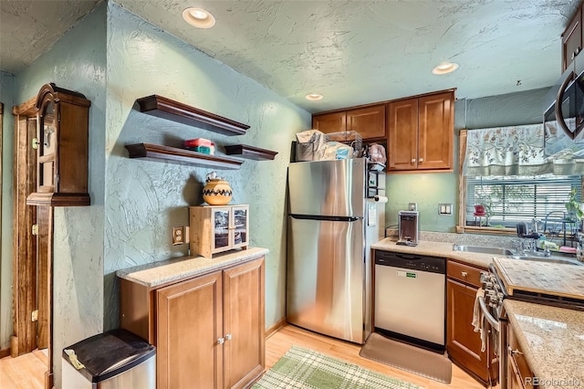 5704 Ammons St, Arvada, CO 80002 - kitchen featuring stainless steel appliances, light wood finished floors, light countertops, a textured wall, and recessed lighting
