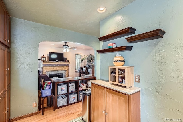 5704 Ammons St, Arvada, CO 80002 - bar with arched walkways, light wood-style flooring, ceiling fan, a fireplace, and a textured wall