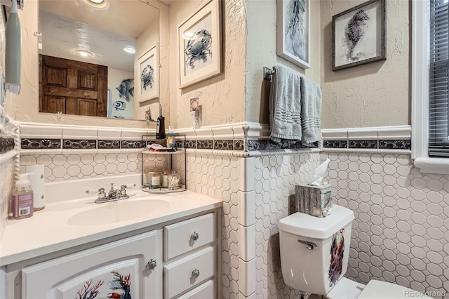 5704 Ammons St, Arvada, CO 80002 - half bathroom with tile walls, wainscoting, toilet, vanity, and recessed lighting