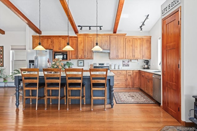 kitchen featuring under cabinet range hood, stainless steel appliances, light countertops, beam ceiling, and light wood finished floors