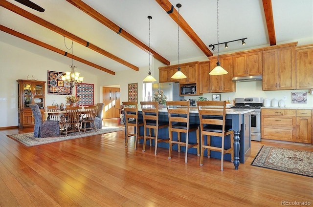 kitchen with stainless steel appliances, light wood-style flooring, under cabinet range hood, and a breakfast bar area