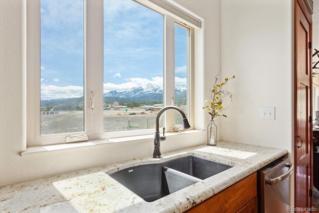 kitchen featuring brown cabinetry, a healthy amount of sunlight, a sink, and a mountain view