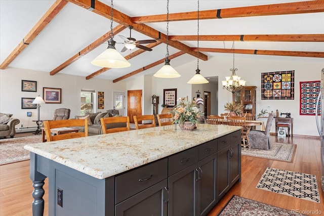 kitchen featuring open floor plan, light stone counters, light wood-type flooring, and decorative light fixtures