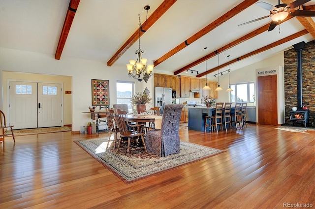 dining room featuring a wood stove, light wood-type flooring, and beam ceiling