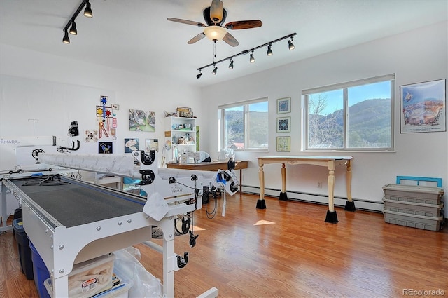 rec room featuring a baseboard radiator, wood finished floors, a ceiling fan, and rail lighting