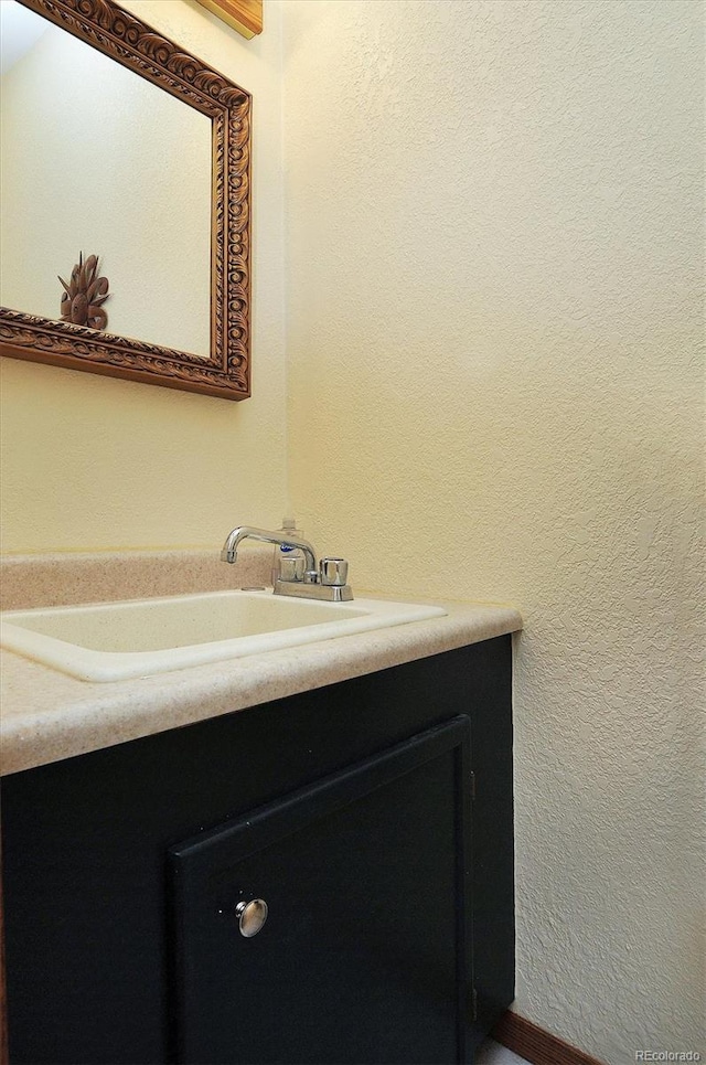 bathroom with a textured wall and vanity