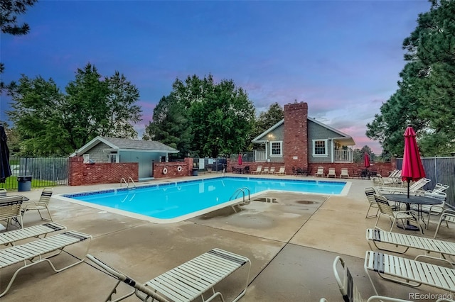 pool at dusk with a patio area