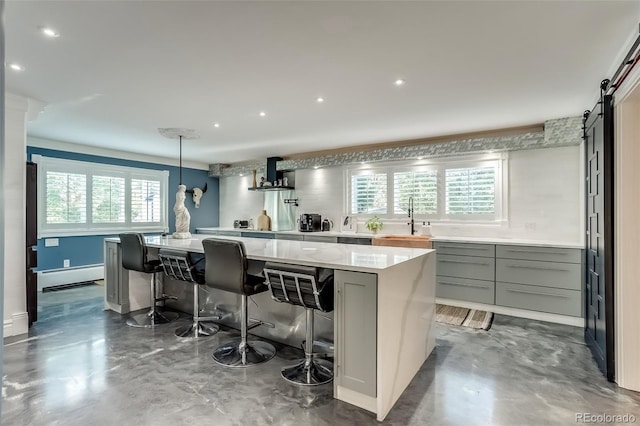 kitchen with gray cabinetry, plenty of natural light, a kitchen island, and a barn door