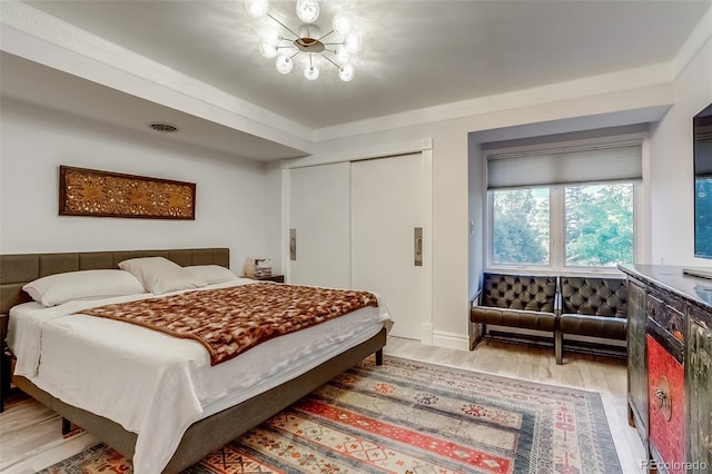 bedroom featuring crown molding, hardwood / wood-style flooring, a notable chandelier, and a closet