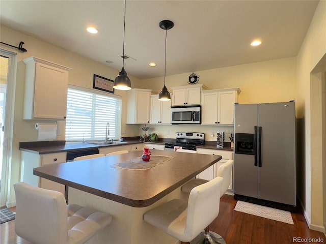 kitchen featuring a sink, stainless steel appliances, a kitchen bar, and dark countertops