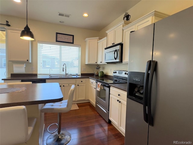 kitchen with a sink, dark countertops, stainless steel appliances, visible vents, and recessed lighting