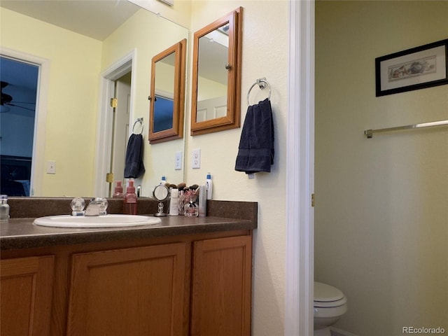 bathroom featuring toilet, vanity, and ceiling fan