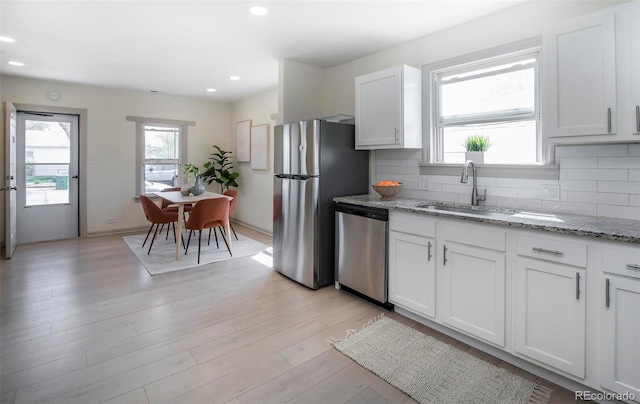 kitchen featuring white cabinetry, appliances with stainless steel finishes, a sink, and tasteful backsplash