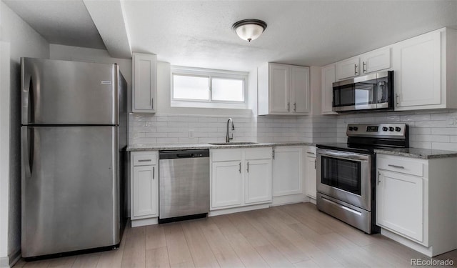 kitchen with a sink, backsplash, light stone countertops, and stainless steel appliances