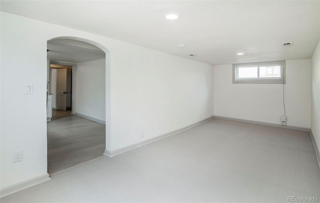 spare room with baseboards, arched walkways, recessed lighting, and light colored carpet
