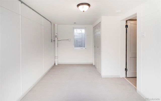 corridor with baseboards and light carpet