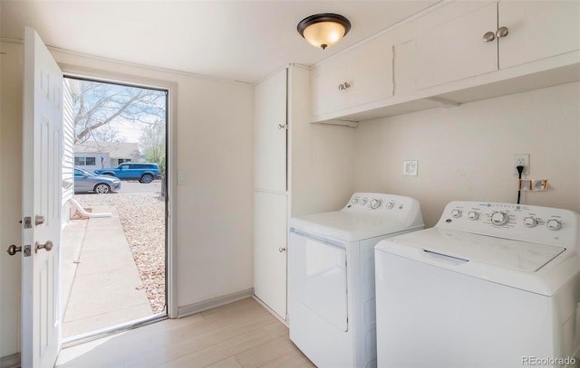 clothes washing area featuring light wood finished floors, cabinet space, and washer and dryer