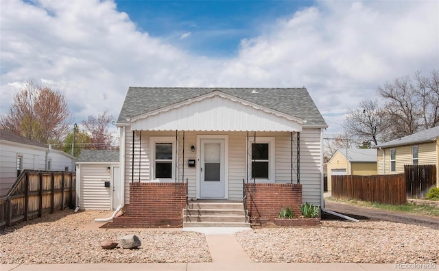 bungalow featuring a porch, fence, and roof with shingles