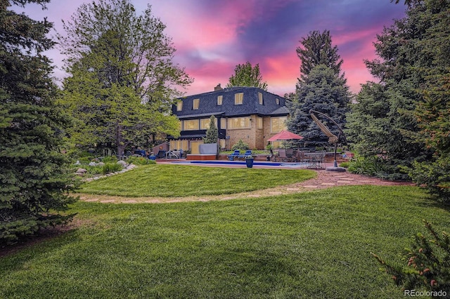 6451 Crestbrook Dr, Morrison, CO 80465 - back of property at dusk featuring a lawn, an outdoor pool, a chimney, and brick siding