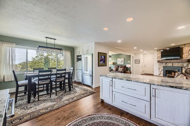 6451 Crestbrook Dr, Morrison, CO 80465 - kitchen with high quality fridge, a fireplace, white cabinets, dark wood-style floors, and open floor plan