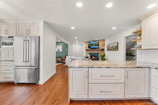 6451 Crestbrook Dr, Morrison, CO 80465 - kitchen with appliances with stainless steel finishes, a peninsula, a stone fireplace, recessed lighting, and light stone counters