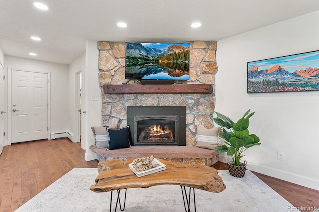 6451 Crestbrook Dr, Morrison, CO 80465 - living area with a baseboard radiator, a stone fireplace, wood finished floors, and recessed lighting