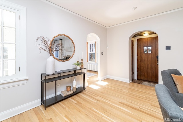 foyer with radiator, crown molding, and hardwood / wood-style floors