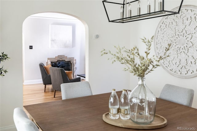 dining area with a stone fireplace and wood-type flooring