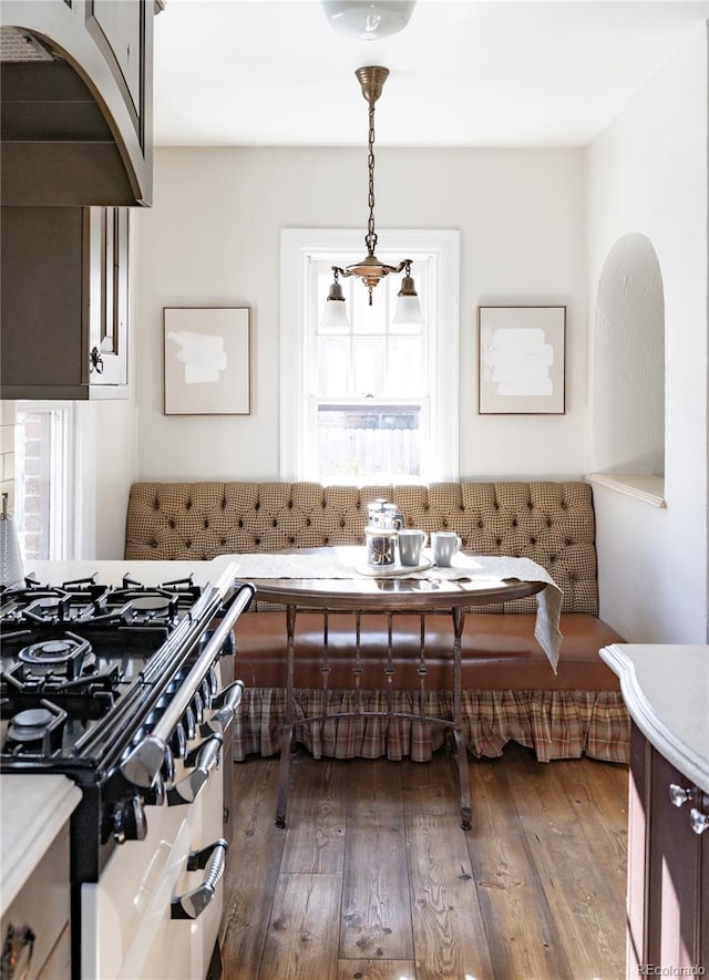 interior space with hardwood / wood-style flooring, breakfast area, high end range, and decorative light fixtures