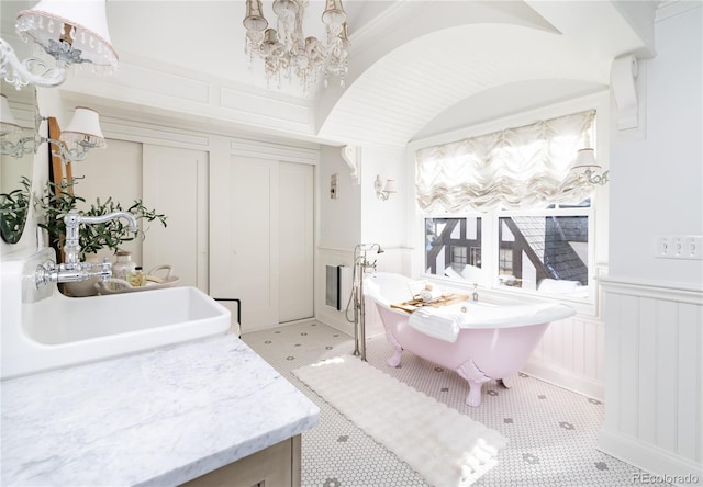 bathroom with tile patterned floors, vanity, a bath, and a chandelier