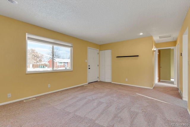 carpeted empty room featuring a textured ceiling