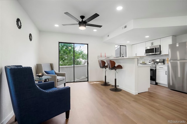 8701 Huron St Unit 2-106, Thornton, CO 80260 - kitchen with appliances with stainless steel finishes, a breakfast bar area, light wood-style flooring, a peninsula, and a ceiling fan