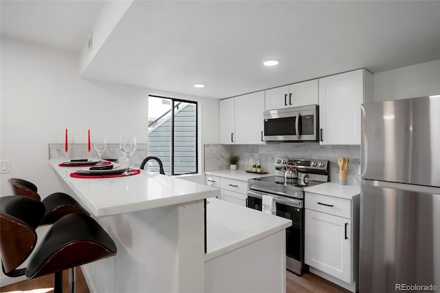 8701 Huron St Unit 2-106, Thornton, CO 80260 - kitchen with stainless steel appliances, a breakfast bar area, a peninsula, tasteful backsplash, and light countertops