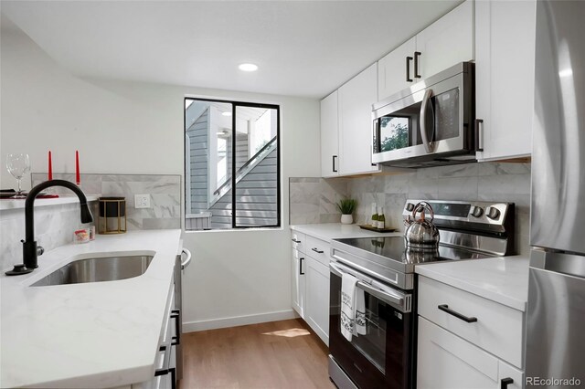 8701 Huron St Unit 2-106, Thornton, CO 80260 - kitchen featuring stainless steel appliances, light wood-style flooring, backsplash, white cabinetry, and recessed lighting