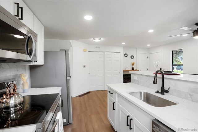 8701 Huron St Unit 2-106, Thornton, CO 80260 - kitchen featuring stainless steel appliances, decorative backsplash, light countertops, wood finished floors, and white cabinetry