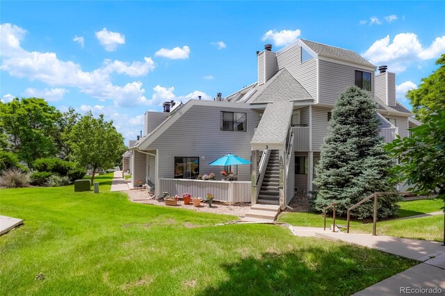 8701 Huron St Unit 2-106, Thornton, CO 80260 - rear view of property with a chimney, a yard, stairs, and roof with shingles