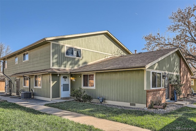 view of front of house featuring a shingled roof, central air condition unit, and a front yard