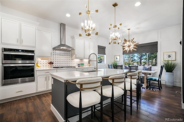 1004 Tree Bark Ter, Colorado Springs, CO 80921 - kitchen featuring wall chimney exhaust hood, a sink, a chandelier, gas cooktop, and light countertops