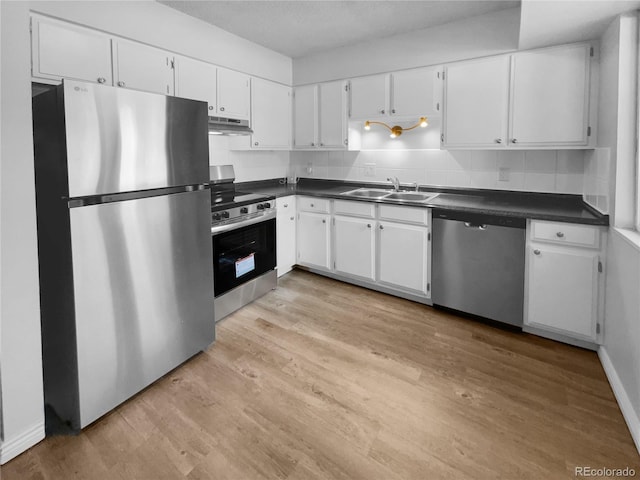 kitchen with decorative backsplash, white cabinetry, appliances with stainless steel finishes, light wood-type flooring, and sink