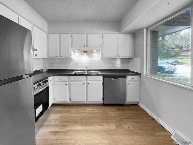 kitchen featuring light wood-type flooring, appliances with stainless steel finishes, sink, and white cabinetry