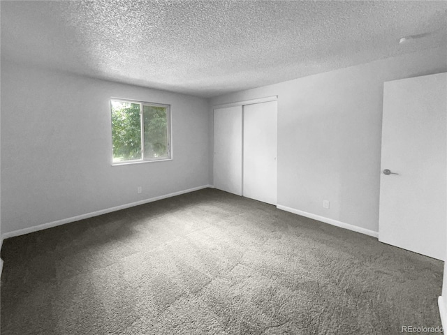 empty room with a textured ceiling and dark colored carpet