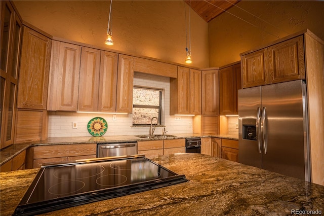 kitchen with stainless steel appliances, hanging light fixtures, sink, and dark stone countertops