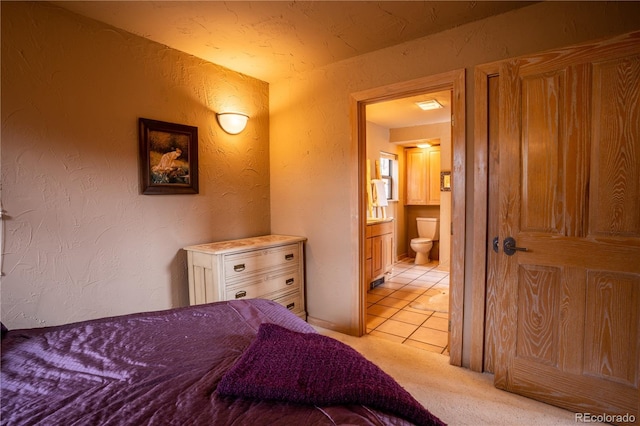 bedroom featuring light colored carpet and ensuite bathroom