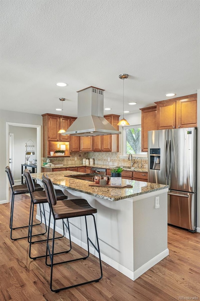 3570 E Arapahoe Pl, Centennial, CO 80122 - kitchen featuring stainless steel refrigerator with ice dispenser, island range hood, brown cabinetry, a kitchen island, and light wood-style flooring